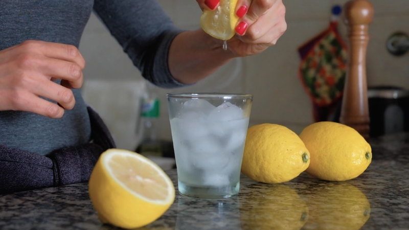 Žena cedi limun u vodu